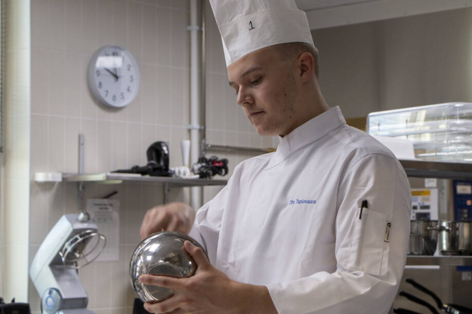Otto Tapiovaara kokkaa keittiössä.