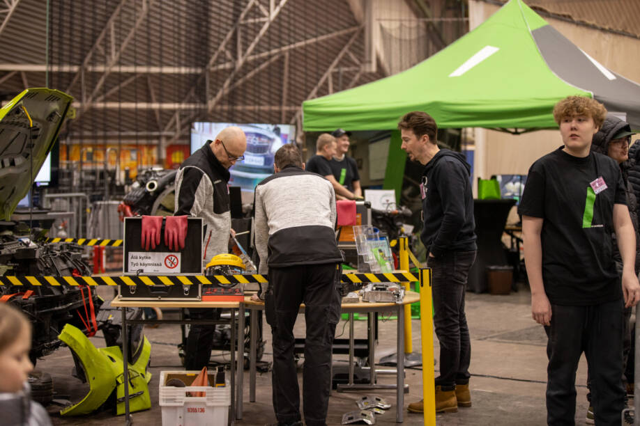 Autopuolen opettajia WinNovan messuosastolla tutkimassa sähköauton osia.